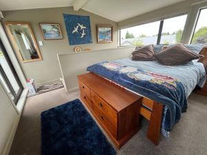 a bedroom with a bed with a dresser and a window at Pet Friendly Country Cottage in Dunedin