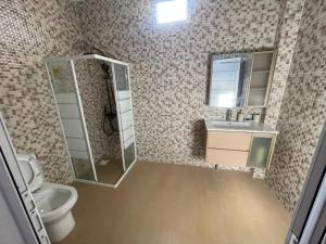 a bathroom with a shower and a toilet and a sink at Villa Aida in Djilore