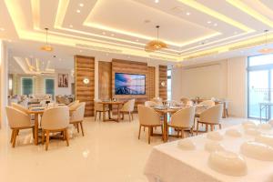 a restaurant with tables and chairs and a flat screen tv at Golden Pillar Hotel in Aqaba