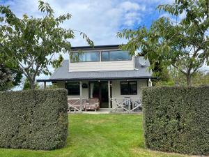 a house with two hedge spheres in front of it at Pet Friendly Country Cottage in Dunedin