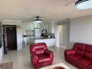 a living room with red chairs and a kitchen at 34 Laguna La Crete in Uvongo Beach
