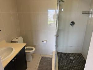 a bathroom with a shower with a toilet and a sink at 34 Laguna La Crete in Uvongo Beach