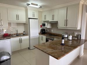 a kitchen with white cabinets and a granite counter top at 34 Laguna La Crete in Uvongo Beach +3 photos