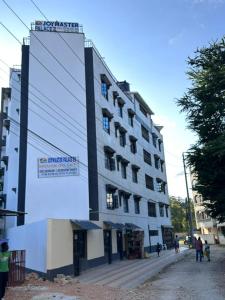 a tall building with people standing outside of it at cozy 1bedroom mombasa bamburi near the beach with hot shower, Netflix, Secured parking 07&07 for 95 then 61to18 in Mombasa