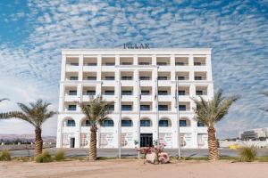 a white hotel with palm trees in front of it at Golden Pillar Hotel in Aqaba