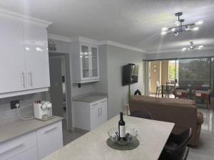 a kitchen and living room with a table with a bottle of wine at 64 Laguna La Crete in Uvongo Beach