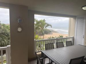 a balcony with a table and chairs and a view of the beach at 64 Laguna La Crete in Uvongo Beach