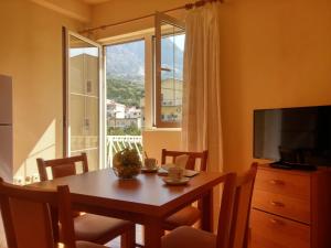 a dining room with a table and a window at Apartments Biser in Podgora