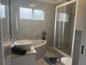 a bathroom with a tub and a sink and a shower at 64 Laguna La Crete in Uvongo Beach +8 photos