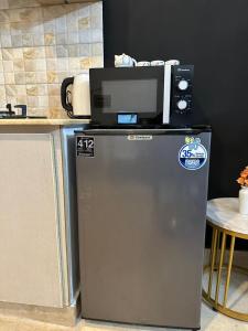 a refrigerator with a microwave on top of it at AuraStays in Dargai