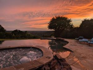 a swimming pool with a sunset in the background at Wildcatter Ranch and Resort in Graham