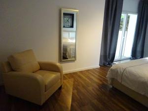 a bedroom with a bed and a chair and a mirror at Apartment Rheintalblick 2 by Interhome in Linz am Rhein