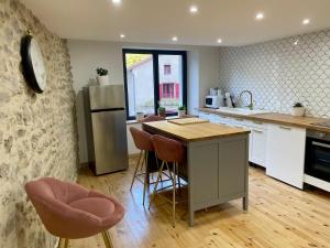 a kitchen with a island with chairs and a refrigerator at Maison de charme - Le Palha in Blesle