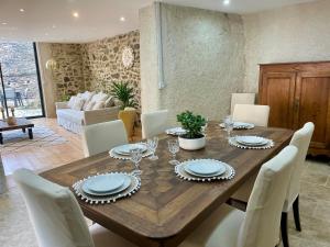 a dining room with a wooden table and white chairs at Maison de charme - Le Palha in Blesle