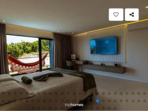 a bedroom with a bed and a tv and a window at Mansão 5 Suítes - Piscina - Cozinheira - até 16 pessoas - Praia Milionários - Ilheus in Ilhéus