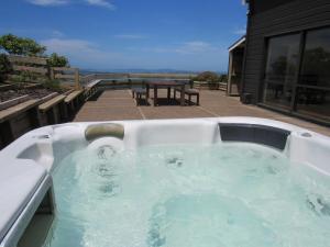 a large hot tub in a backyard with a table at Pine Holt Cottage in Warkworth