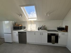 a kitchen with white cabinets and a sink and a window at Pine Holt Cottage in Warkworth
