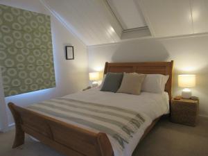 a bedroom with a large bed with two lamps at Pine Holt Cottage in Warkworth