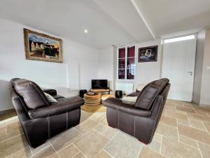 a living room with two leather chairs and a television at Gite De L'Aeti - Bail Partner in Chablis