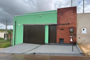 a building with a green door and a brick wall at Casa Simples e Funcional em Araxá in Araxá
