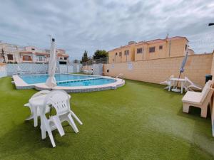a patio with white chairs and a swimming pool at Rosa de la Sal in La Mata