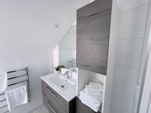 a white bathroom with a sink and a mirror at STUDIO42 in Papakura +5 photos