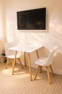 a white table with two chairs and a tv on a wall at Dpto SAN MARTIN in Azul
