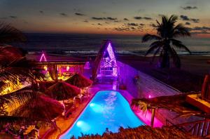 a resort with a swimming pool and the beach at night at baXar in Pie de la Cuesta