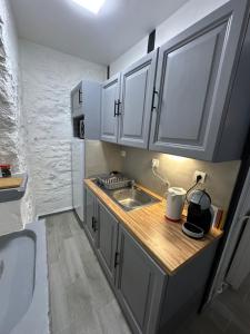 a small kitchen with white cabinets and a sink at Duplex au cœur de la Bastide in Villefranche-de-Rouergue