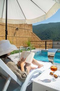 a woman sitting in a chair reading a book by a pool at Zeyzid Glamping Sheki in Sheki