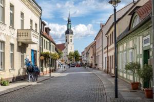 a cobblestone street in a town with a clock tower at Spreezauber in Lübbenau