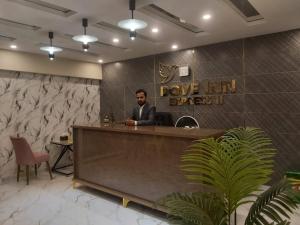 a man in a suit sitting at a reception desk at Dove INN Express II in Lahore