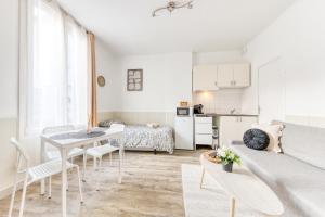 a white living room with a couch and a table at Le Signature Studio in Dreux