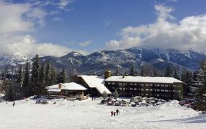 a ski lodge in the snow with mountains in the background at Griz Inn by Fernie Central Reservations - Right on The Slopes in Fernie