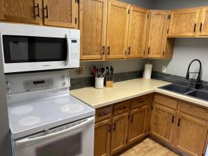 a kitchen with white appliances and wooden cabinets at Griz Inn by Fernie Central Reservations - Right on The Slopes in Fernie