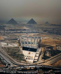 an aerial view of a building with pyramids in the background at Grand Museum Guest House in Kafr Abū ʼumaydah