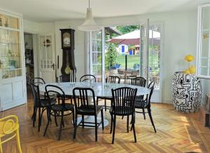 a dining room with a table and chairs and a clock at La Villa Rose in Blaye