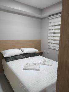 a bedroom with a bed with white sheets and a window at Studio Flat - Guarulhos -Airport Aeroporto - Bosque Maia - Cidade Maia in Guarulhos +19 photos