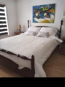 a bedroom with a large bed with a painting on the wall at Villa le Voyageur in Sherbrooke
