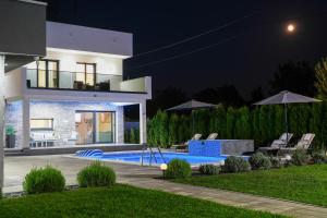 a villa with a swimming pool at night at LUXIA PRIVATE ESTATE Sauna & Pool x Jacuzzi with Fireplace outdoor lounge in Bihać
