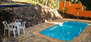 a pool with a table and chairs and an umbrella at Pousada Mirante Do Lago in Lindóia
