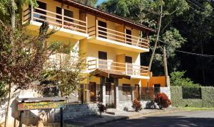 a yellow building with a balcony on a street at Pousada Mirante Do Lago in Lindóia
