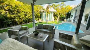 a patio with a couch and chairs next to a pool at Lagoon Poolvillas Pattaya in Ban Huai Yai