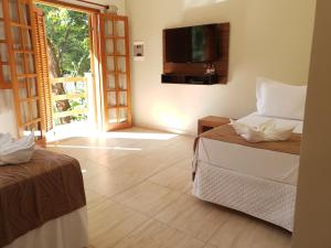 a room with two beds and a television on the wall at Pousada Mirante Do Lago in Lindóia