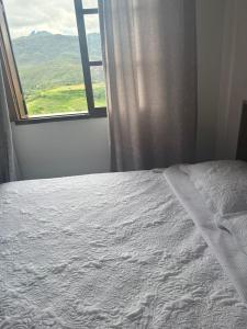 a bedroom with a white bed with a window at Maxi conforto e vista para o Itacolomi in Ouro Preto