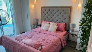 a bedroom with a large bed with pink sheets and pillows at Lagoon Poolvillas Pattaya in Ban Huai Yai +120 photos
