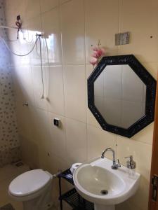 a bathroom with a sink and a toilet and a mirror at Casa para diarias e empresas in Cianorte