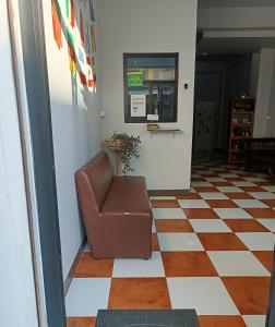a leather chair in a hallway with a checkered floor at เส้นดี โฮสเทล Sendee Hostel in Phitsanulok