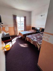 a hotel room with two beds and a window at Hotel Mesón del Rey in Oaxaca City