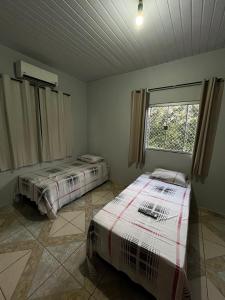 two beds in a room with a window at Pousada Gaivota in Trindade